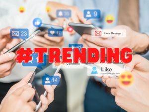 Blurred photo of hands holding phones with notification bubbles. '#Trending' is written in red across the image.